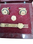 CONJUNTO DE ABOTOADURAS E ALFINETE  COMITÉ OLÍMPICO DA BIELORRÚSSIA Conjunto oficial do Comité Olímpico da Bielorrússia em estojo de veludo, incluindo par de abotoaduras, alfinete de gravata e insígnia de lapela com acabamento dourado.