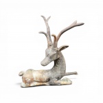 Escultura de cervo reclinado em bronze fundido e cinzelado  com expressiva estilização na galhada e na textura da pelagem do pescoço. Apresenta marcas incisas ornamentais nas laterais e pátina natural do tempo. Medidas: 40 x 40 cm ,   no estado.