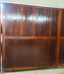 MADEIRA ANGELIM - ANTIGA FOLHA DE PORTÃO EM MADEIRA DE LEI ENVERNIZDA com rodízios - 220x205 cm - necessitando renovar verniz na parte externa e faltando pequeno pedaço na parte externa inferior próximo ao rodizio lado direito causado pela ação do tempo conforme foto.   - NÃO ACOMPANHA TRILHO - faz conjunto com lotes 3 e 5 desse catálogo.