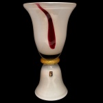 Belíssimo vaso em vidro artístico de Murano, construído com duas partes superpostas e lisas moldadas no formato de sino, reunidas por adorno anelado ornamentado por flocos em ouro 24 K. Bojo com boca em corneta, ornado por estilização escorrida de cor grená. Base com borda inferior esparramada. 48 x 26 cm. Passamos para informar os detalhes e o procedimento para a retirada do seu lote: O lote encontra-se originalmente em Belo Horizonte (MG). e estará disponível em nosso escritório em São Paulo (SP) a partir de uma semana após o término do leilão. A retirada deve ser feita exclusivamente mediante agendamento prévio. Telefone para agendamento: (11) 5044-1228. Por favor, entre em contato conosco pelo telefone acima para escolher o melhor dia e horário para buscar o seu lote.