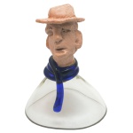 MARIO SEGUSO. Vintage  Peça de decoração de formato cônico em vidro artístico de Murano realçado por detalhe de cor azul. Parte superior ornada por cabeça masculina em cerâmica, apoiada em adorno espiralado de cor azul. Assinada. 16 x 12 cm. Passamos para informar os detalhes e o procedimento para a retirada do seu lote: O lote encontra-se originalmente em Belo Horizonte (MG). e estará disponível em nosso escritório em São Paulo (SP) a partir de uma semana após o término do leilão. A retirada deve ser feita exclusivamente mediante agendamento prévio. Telefone para agendamento: (11) 5044-1228. Por favor, entre em contato conosco pelo telefone acima para escolher o melhor dia e horário para buscar o seu lote.