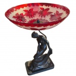 Original fruteira montada com bowl em cristal revestido por overlay vermelho, ornamentada por larga faixa com composições florais e bordada por friso de folhagens. Base com escultura em bronze patinado, representado figura feminina de pé com joelho dobrado, segurando grande lenço na mão. Peanha retangular em granito preto. 50 x 40 x 24 cm (MT).  Passamos para informar os detalhes e o procedimento para a retirada do seu lote: O lote encontra-se originalmente em Belo Horizonte (MG). e estará disponível em nosso escritório em São Paulo (SP) a partir de uma semana após o término do leilão. A retirada deve ser feita exclusivamente mediante agendamento prévio. Telefone para agendamento: (11) 5044-1228. Por favor, entre em contato conosco pelo telefone acima para escolher o melhor dia e horário para buscar o seu lote.