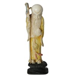 Estatueta chinesa em marfim policromado representando Shouxing, o deus chinês da longevidade, com pêssego da Imortalidade na mão esquerda e cajado na outra. Acompanha peanha em madeira.O pêssego na mão esquerda trata-se do pêssego sagrado da imortalidade, oriundo dos pomares celestiais da Rainha Mãe do Ocidente. O cajado na mão direita representa a sua jornada como um sábio idoso que caminha pelo mundo dos mortais levando bênçãos de saúde.