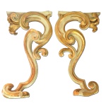 Imponente par de talhas de parede em madeira patinada com realces a ouro, esculpidas com volutas superpostas e entrelaçadas. Partes superiores rematadas por folhagens, sustentando pequenas prateleiras lisas. Peças Atribuídas ao Mestre Valentin. 85 x 48 x 12 cm.