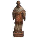 Séc. XIX - Bela e rara imagem em madeira esculpida, policromada e dourada representando São Raimundo Nonato. Exibe ricas vestes sacerdotais, profusamente bordadas e rendadas, compostas de uma longa alva plissada, uma tunicela, um curto manto sobre os ombros e um capuz por traz da cabeça. É retratado com os braços abertos, de pé sobre uma base chanfrada em madeira. Notam-se as feições acentuadas, porém tranquilas do rosto, assim como a profunda fixação do olhar. Faltam as mãos. Traz numeração de colecionador sob a base. 51 x 18 x 10 cm.