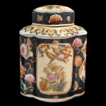 Pote com tampa em porcelana oriental decorado com pintura policromada de pássaros e flores em reservas sobre um fundo escuro. Corpo com desenho sextavado e tampa correspondente. Painéis centrais claros com ilustrações de aves e vegetação, emoldurados por detalhes florais sobre um fundo preto ou azul escuro. 23 x 18 x 13 cm.