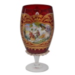Taça em cristal veneziano  na cor vermelho rubi profundo. Apresenta farta douração aplicada à mão com relevos de arabescos e motivos decorativos rococó. Bojo apresentando  medalhão central pintado à mão, retratando uma cena galante de época. Base circular translucida e circular. 17 x 8 cm.