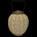 Biscoiteira em vidro opalinado amarelada na cor amarelada (milk glass). Apresenta ornamentos em alto relevo com motivos de folhagens que se assemelham ao formato de uma grande noz. Tampa removível e uma alça de transporte articulada feitas em metal. 24 cm (só a peça). 31 x 18 cm (MT).