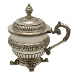 PEÇA DE COLEÇÃO - PRATA 10 DINHEIROS. RIO DE JANEIRO, Ourives JOSÉ FERNANDES DE CARVALHO. Circa 1847 / 1853 - Cuspideira em prata brasileira repuxada e cinzelada, ornamentado por faixas com gomos alternadas por frisos florais. Bojo cônico e abaulado, com alça lateral em S rematada por cabeça de golfinho. Tampa abobadada no estilo, encimada por pega em pião. Base circular almofadada apoiada em pés de garra. Contraste 10 Dinheiros e marca do prateiro F. C. (José Fernandes de Carvalho). Circa de 1847 / 1853. Marcas reproduzidas no Livro do Moitinho BR-1248 pág. 377 / BR-49 pág. 354. Coleção Ari Bragança de Bourbon. 16 x 16 cm. Peso 560 gramas.