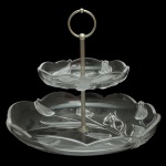 Centro de mesa com dois estágios em espesso vidro translúcidos com delicados relevos de tulipas nas bordas e uma haste metálica central com argola. 27 x 30 cm.