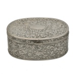 Caixa de formato ovalado  em metal prateado detalhadamente trabalhado com relevos e arabescos em sua superfície. 5 x 11 x 8 cm. Espólio de Josephina Penteado da Fonseca, SP.