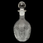 Elegante licoreira em cristal transparente com lapidação geométrica e tampa facetada em formato de esfera. 27 x 12 cm. Espólio de Josephina Penteado da Fonseca, SP.