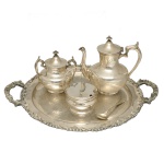 Serviço para café em metal prateado, composto por 5 peças de diferentes manufaturas, sendo: 1 bandeja oval com alças (50 x 40 cm), 1 bule para café (20 x 20 cm e 1 açucareiro (15 x 14 cm) da mesma manufatura, 1 pote para queijo (16 x 11 cm) e 1 colher para açúcar. Manufaturas diferentes. Espólio de Josephina Penteado da Fonseca, SP.
