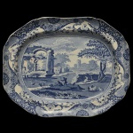 Inglaterra. Séc. XIX - Travessa em louça da icônica coleção Spode Blue Italian. Padrão apresentando uma cena detalhada de ruínas clássicas italianas em tons de azul cobalto e branco, emoldurada por uma intrincada borda inspirada no design oriental com arabescos. 37 x 47 cm. Verso com um pequeno carimbo na cerâmica esmaltada com pátina de envelhecimento e leves manchas na base. Espólio de Josephina Penteado da Fonseca, SP.