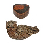 Conjunto de dois objetos decorativos, sendo: A) Porta-joias na forma de coração laqueada, decorada com uma pintura detalhada de rosa alaranjada no topo. 4 x 12 x 13 cm. B) Caixa decorativa na forma de uma coruja deitada, confeccionada em material sintético imitando traços esculpidos e texturas naturais. 12 x 25 x 12 cm. Espólio de Josephina Penteado da Fonseca, SP.