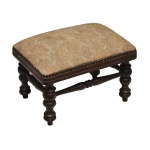 Pequena banqueta para os pés, de formato retangular, com estrutura em madeira nobre. Assento estofado e tacheado em tecido floral, estampado em tons pasteis sobre fundo creme. Saia lisa apoiada em largos pés torneados e anelados, reunidos por traves seguindo o estilo. 24 x 35 x 25 cm. Espólio de Josephina Penteado da Fonseca, SP.