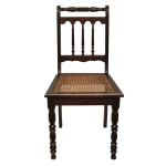 Original cadeira em madeira escurecida, estilo eclético. Encosto com laterais retas, reunidas por cachaço horizontal anelado. Tabela ornada por balaústre com 3 colunatas. Assento em palhinha da Índia, apoiado em saia lisa. Pernas dianteiras retilíneas e torneadas. Transição séc. XIX - séc. XX. 90 x 45 x 42 cm. Espólio de Josephina Penteado da Fonseca, SP.
