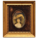 Miniatura de formato retangular em madeira retratando uma elegante dama de época com um chapéu de abas largas. pintado em porcelana emoldurado de forma ornamental. 8 x 6 cm (MI). 20 x 17 cm (ME). Espólio de Josephina Penteado da Fonseca, SP.