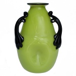 Vaso piriforme em cristal de cor verde Chartreuse. Bojo moldado com cavidades laterais na base e ladeado por largas e originais alças pretas rematadas por garras. Gargalo retraído, encimado por borda revirada realçada por filete. 22 x 14 cm.