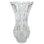 Vaso em cristal transparente da Boêmia, de formato balaústre, profusamente lapidado com gomos e facetas, realçadas por adornos estrelares e raiados. Bojo em corneta com borda dentada, apoiado em base saliente e abaulada. 21 x 11 cm.