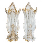 Séc. XIX - Par de antigas e elegantes floreiras em porcelana Vieux Paris, decoradas por adornos e frisos a ouro. Bojos alongados em cornetas, moldados por finos gomos, ladeados por alças vazadas e realçados por motivos florais com treliças douradas. Bordas movimentadas e recortadas em pétalas. Bases onduladas e arqueadas com pés revirados. 28 x 10 x 9 cm.