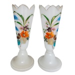 Par de floreiras em vidro artístico, decoradas por arranjos florais policromados. Bojos cônicos encimados por bordas dentadas e douradas. Bases circulares com centros elevados. Cerca 1900. 31 x 12 cm.