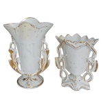 Conjunto de 2 vasos de altar em porcelana Vieux Paris, realçados por detalhes dourados. Bojos moldados em cornetas com bordas recortadas, sendo um ladeado por folhagens e espigas de trigo, com nome Jesus à frente e base circular. O outro, com hastes laterais entrecruzadas e pés recortados. Final do séc. XIX. 23 x 17 x 9 cm maior / 17 x 14 x 8 cm menor. Amas apresentam restauros.