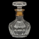 Decanter em cristal translucido e lapidações.   Apresenta virola metálica em metal dourado no bocal e tampa achatada. 20 x 13 cm.