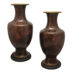 Par de vasos chineses, de formato balaústre, decorados em esmaltes cloisonnés. Apresentam composições florais sobre fundo chocolate. Bojos abaulados, encimados por gargalos em cornetas e bordas reviradas. Bases esparramadas e circulares. Acompanham peanhas em madeira. 40 x 17 cm.