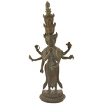 Escultura devocional budista de divindade com cabeças em camadas e vários braços rituais (Avalokiteshvara - Bodhisattva da compaixão). Metal patinado com acabamento escurecido, braços abertos segurando atributos simbólicos e base detalhada. Arte asiática tradicional inspirada em iconografia tibetana ou do Sudeste Asiático. 58 x 27 x 9 cm.