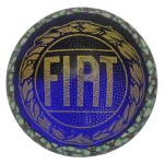 Peso de papel circular, em cristal de Murano de cor azul com realces dourados. Apresenta emblema da Fiat emoldurado por coroa de louros. Assinado ALT Murano. 6 x 9 cm.
