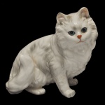 Estatueta em porcelana retratando um gato persa branco, sentado de pelos longos e olhos azuis. Sem marca, com numeração.