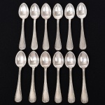 FAQUEIRO, doze (12) colheres de café, confeccionadas em metal prateado, ornamentação relevada no padrão Império Napoleônico em frisos intercalados por X com terminações em concha e laçarote, manufatura FRACALANZA (tradição desde 1884), medindo 10 cm comprimento, vide foto.