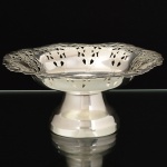 METAL PRATEADO, uma (1) pequena fruteira de pé alto, borda recortada e vazada em silhuetas vegetalistas, marca DOMUS PRATA 90, medindo 15 cm diâmetro e 7 cm altura, vide foto.