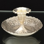 METAL PRATEADO, uma (1) palmatória com ornamentação cinzelada no padrão Império Otomano com elementos geométricos e vegetalistas, além de legendas em árabe, medindo 10 cm diâmetro e 5 cm altura, vide foto.
