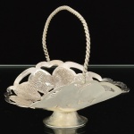 METAL PRATEADO, uma (1) fruteira miniatura de pé baixo, ornamentação vazada em elementos vegetalistas, alça em torçaide, sem marca de manufatura aparente, medindo 7,5 cm altura até a alça, vide foto.