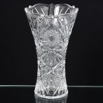 CRISTAL, um (1) vaso floreiro, grosso, incolor e translúcido, moldado em rosáceas, palmas, flores e sulcos, borda recortada, terminando em corneto, medindo 24,5 cm altura, vide foto.
