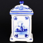 PORCELANA HOLANDESA, uma (1) caixa de chá com tampa, retangular, ornamentação pintada a mão na técnica blue and white, representando paisagem com marina, moinhos e casarios, além de elementos vegetalistas, marcado na base Holland Hand Painted, medindo 14 cm altura, vide foto.