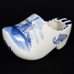 PORCELANA HOLANDESA, um (1) cinzeiro modelado no formato de tamanco, ornamentação pintada a mão na técnica blue and white, representando paisagem com marina, casarios e moinhos, marca de origem DELFT, medindo 16 cm comprimento, vide foto.