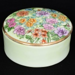 PORCELANA, um (1) potiche com tampa para toucador, ornamentação floral policromada pintada a mão sobre fundo verde, arremates a ouro, marca de atelier MY, sem marca de manufatura aparente, medindo 12,5 cm diâmetro e 5,5 cm altura, vide foto.
