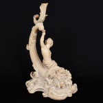ESCULTURA, uma (1) figurativa representando menino com gaiola e pássaro nas mãos, sentado sobre cornucópia de onde saem flores, confeccionada em resina com pó de mármore, medindo 41 cm altura, vide foto.