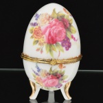 PORCELANA, uma (1) caixa no formato ovoide, ornamentação policromada com florais, faixas na tonalidade azul cobalto, arremates a ouro com pérgulas, volutas e elementos vegetalistas, marca Fine Porcelain Hand Painted  24K Gold Deco Collections LIMOGES, monture em metal dourado, base trípode, medindo 12 cm altura, vide foto.