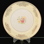 FAIANÇA, um (1) prato raso com ornamentação floral policromada, faixa na tonalidade amarela, barrado vegetalista a ouro, marca EDWIN M KNOWLES CHINA COMPANY (fundada no ano de 1900 em Chester, Virgínia, USA; encerrou as atividades na década de 60), traz o craquejado característico do envelhecimento de toda a faiança, medindo 23,5 cm diâmetro, falhas na douração, vide foto.