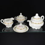 PORCELANA, conjunto de chá com quatro (4) sendo: 1 bule; 1 cremeira; 1 açucareiro e 1 manteigueira, marca SCHMIDT (Pomerode, SC; Mauá, SP; Campo Largo, PR, fundada em 1945, ainda em atividade, maior fábrica de porcelana da América Latina), ornamentação floral policromada, pega da tampa modelada em flor, faixa na tonalidade verde, arremates vegetalistas e detalhes a ouro, medindo a maior peça 15 cm altura, vide foto.