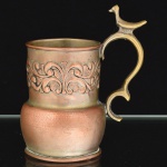 METAL PRATEADO, uma (1) caneca com ornamentação relevada em elementos vegetalistas, demanda novo banho em prata, alça em bronze sinuosa e encimada por pássaro, sem marca de manufatura aparente, medindo 10,5 cm altura até a alça, vide foto.