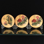 DIVERSOS, três (3) pratinhos confeccionados em fibra de bambu trançada e prensada, ornamentação policromada, dois deles representando flores e um representando cena do gênero, todos com caracteres, medindo 10,5 cm diâmetro, vide foto.