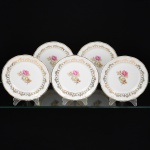 PORCELANA, cinco (5) pratos de sobremesa, ornamentação central com rosas em policromia, barrado em flores e frisos a ouro, marca SCHMIDT (Pomerode, SC; Mauá, SP; Campo Largo, PR, fundada em 1945, ainda em atividade, maior fábrica de porcelana da América Latina), um deles com bicadinho na borda visto pela parte de traz, medindo 18 cm diâmetro, vide foto.