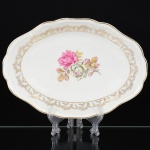 PORCELANA, uma (1) travessa oval de borda alta, ornamentação central com rosas em policromia, barrado em flores e frisos a ouro, marca SCHMIDT (Pomerode, SC; Mauá, SP; Campo Largo, PR, fundada em 1945, ainda em atividade, maior fábrica de porcelana da América Latina), medindo 29 x 20 x 6 cm, vide foto.