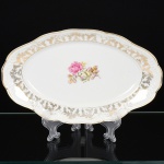 PORCELANA, uma (1) travessa oval, ornamentação central com rosas em policromia, barrado em flores e frisos a ouro, marca SCHMIDT (Pomerode, SC; Mauá, SP; Campo Largo, PR, fundada em 1945, ainda em atividade, maior fábrica de porcelana da América Latina), medindo 29 x 18 cm, vide foto.