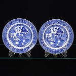 FAIANÇA INGLESA, par (2) pratos de bolo, ornamentação WILLON (Segundo a lenda chinesa: Um certo Mandarim tinha uma leal e devotada filha, possuidora de rara beleza. Certo dia, em que descobre que ela estava apaixonada por um carteiro que lhe fazia a corte, e que era por ela correspondida, expulsa a filha de casa e roga-lhe uma praga: que ao ser trocado o primeiro beijo pelo casal, eles se transformariam em dois pombos), dita POMBINHOS, tonalidade azul e branca, marca WOOD & SONS (fundada em 1865, funcionou na Potteries New Wharf em Trent e mais tarde na Pottery Stanley em Burlem, fechou em 2005), medindo 17 cm diâmetro, vide foto.